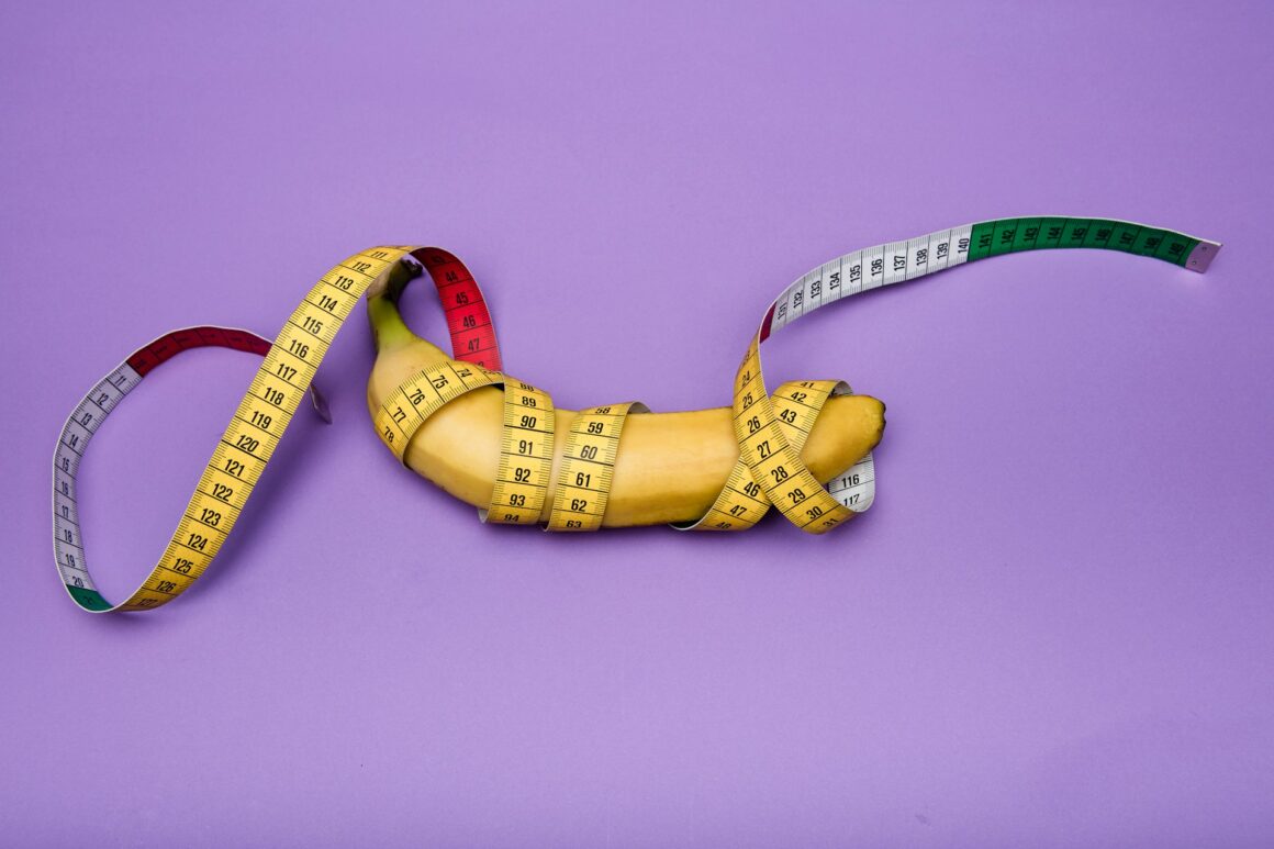 A banana representing a penis on a purple background with a tape measure wrapped around it several times