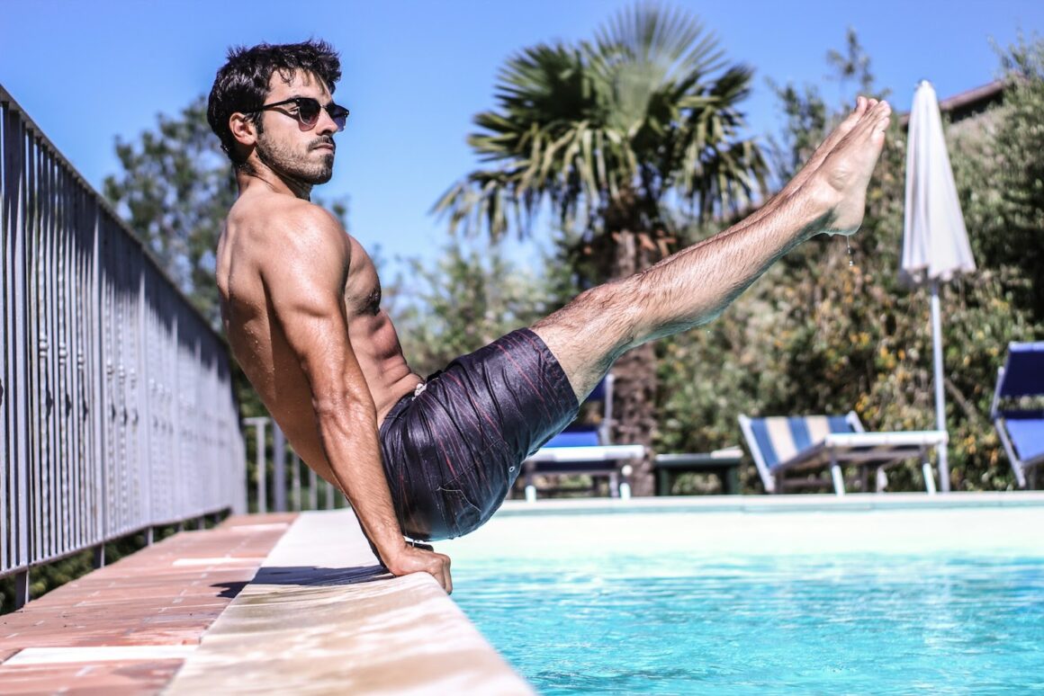 A guy with BDE holding a pose on the edge of a swimming pool