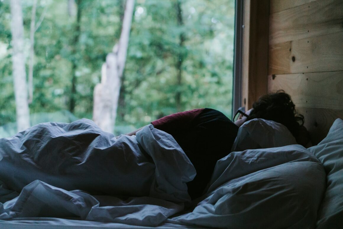 A man looking out into nature from his bed