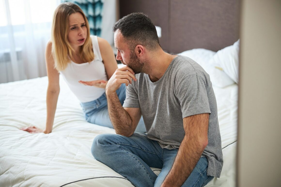 A guy and his girlfriend sit on the bed having a hard talk