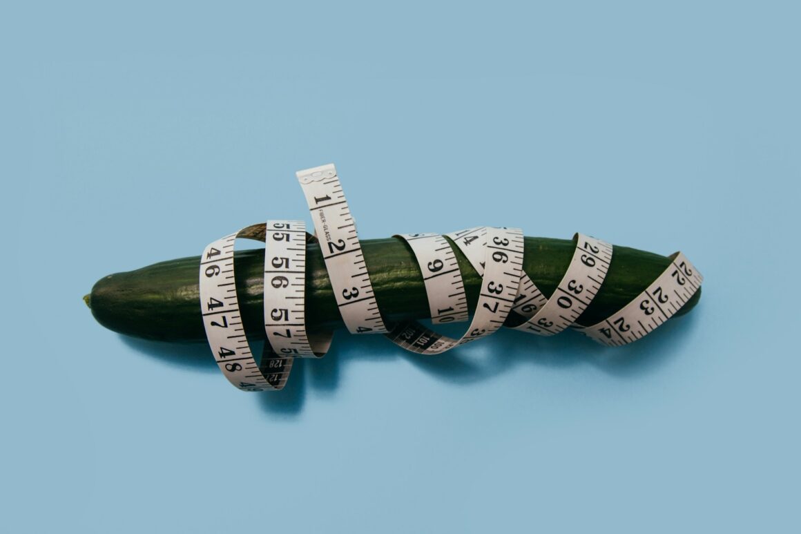 A cucumber representing a penis wrapped in a tape measure