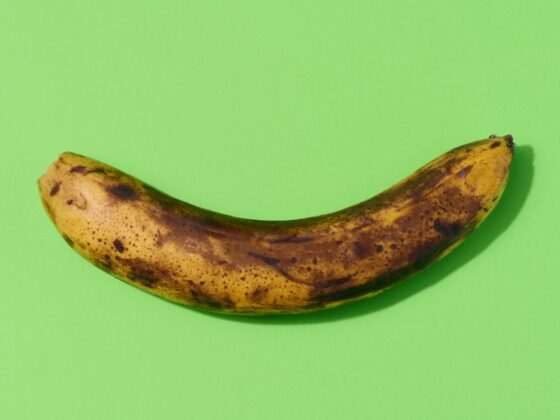 Overripe yellow banana on a green background