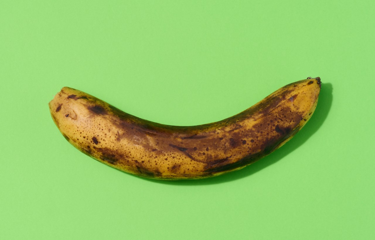 Overripe yellow banana on a green background