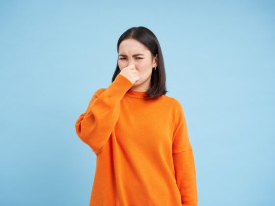 woman shuts her nose with fingers from bad smell