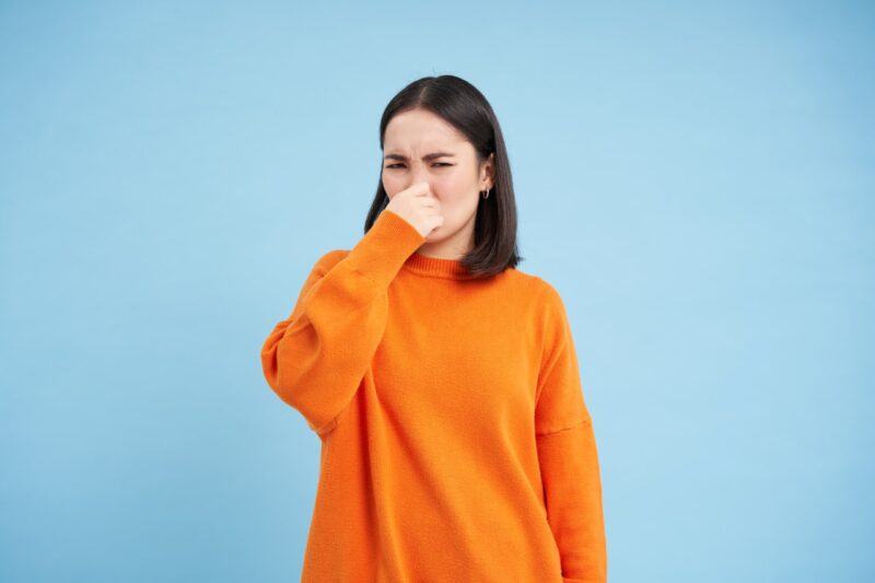 woman shuts her nose with fingers from bad smell