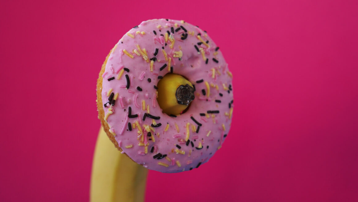 Sweet donut and banana on pink color background