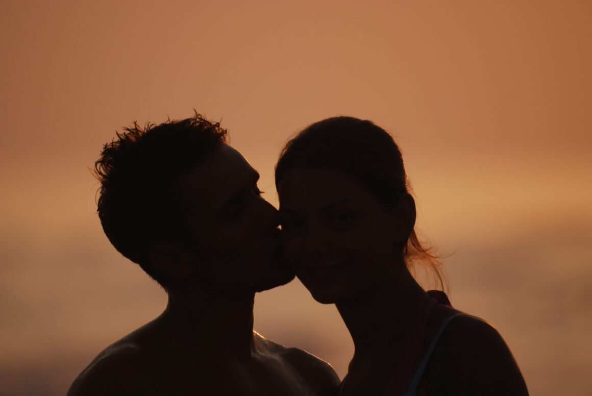 a romantic couple on a beach during sunset