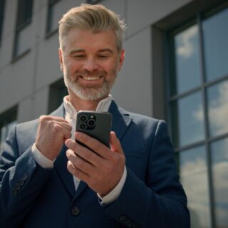 middle aged man looking happy while looking down at his smart phone