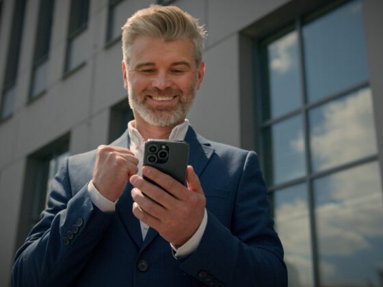 middle aged man looking happy while looking down at his smart phone