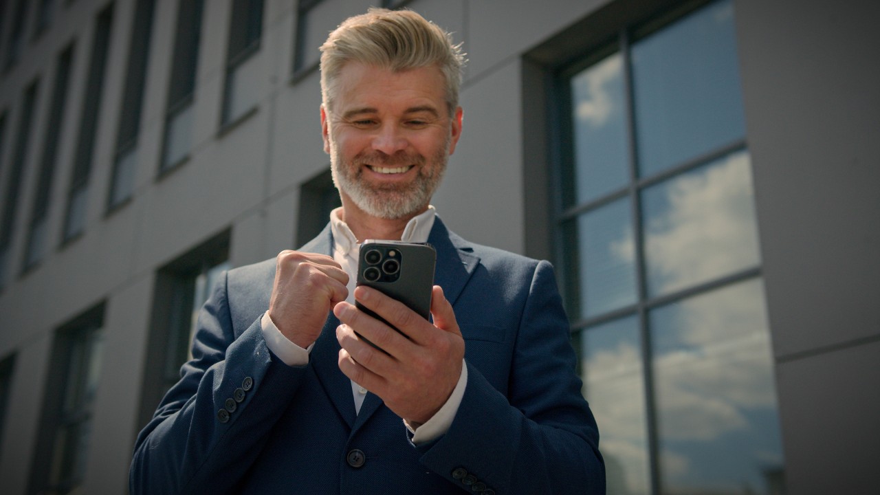 middle aged man looking happy while looking down at his smart phone