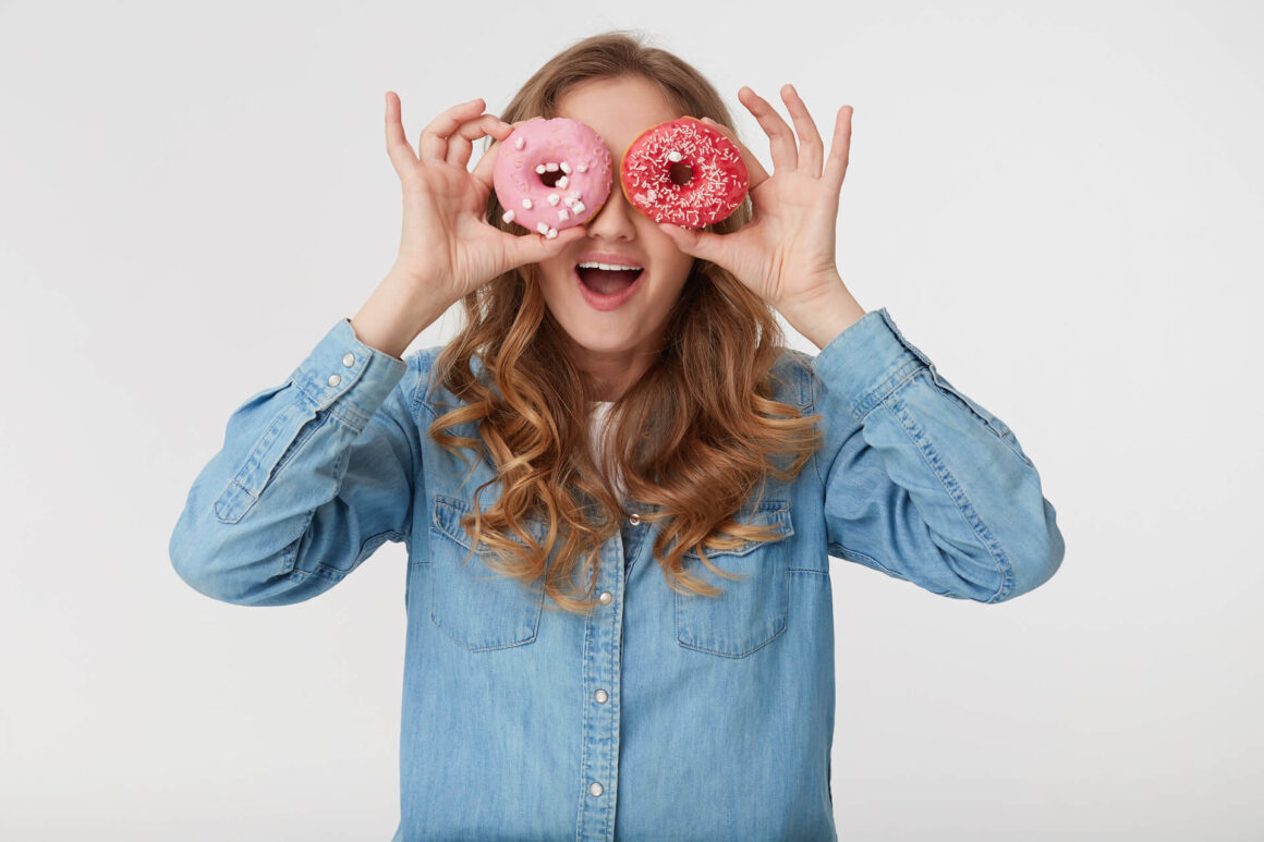 woman holding two donuts at her eyes