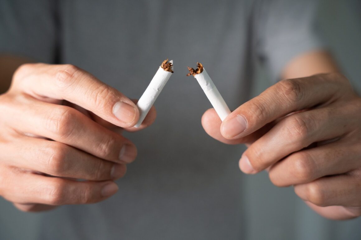 person breaking a cigarette stick in half