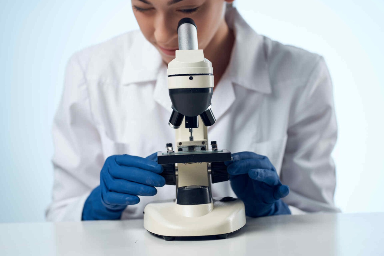 a female doctor looking through a microscope