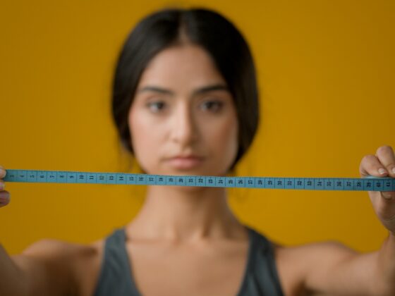 beautiful woman holding a blue colored tape measure