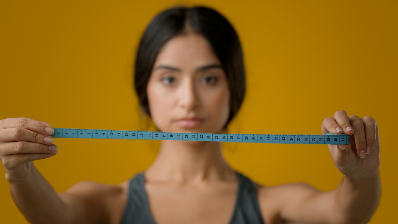 beautiful woman holding a blue colored tape measure