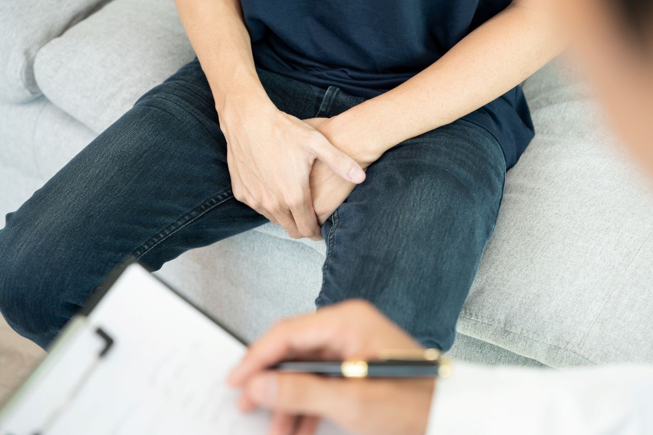 man holding his private part with both hands in discomfort while talking to a doctor