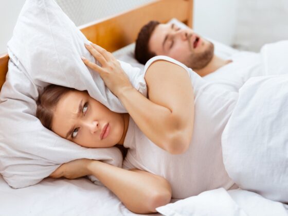 irritated woman lying beside a sleeping man