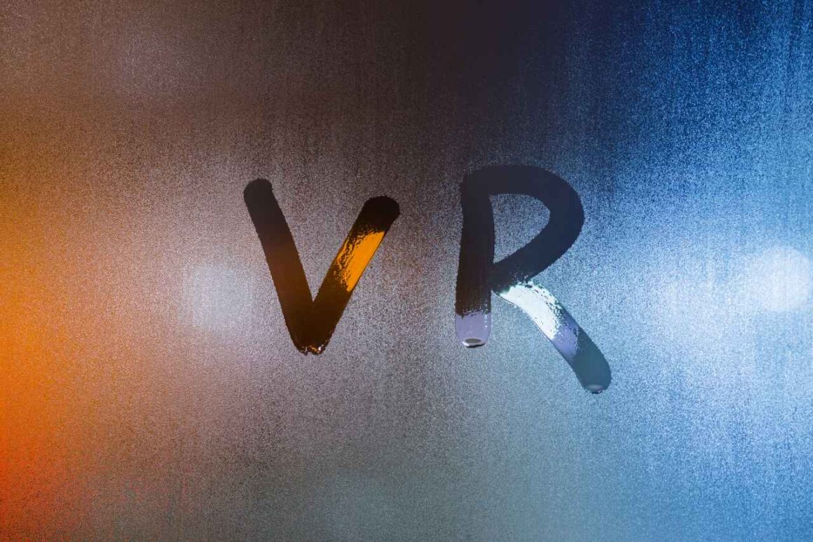 the word vr - virtual reality - written by finger on wet glass with blurred lights in background