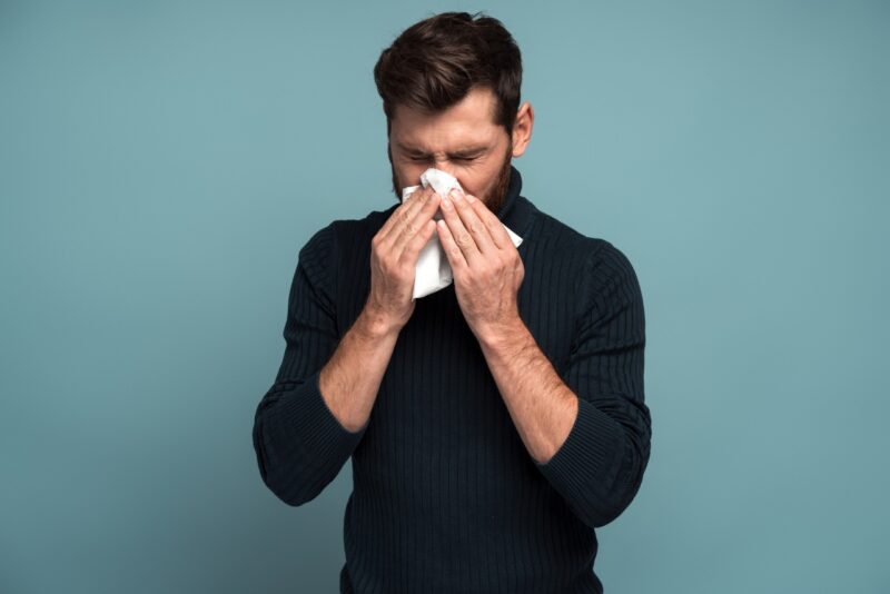 man covering his nose because of allergy