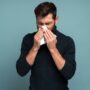 man covering his nose because of allergy