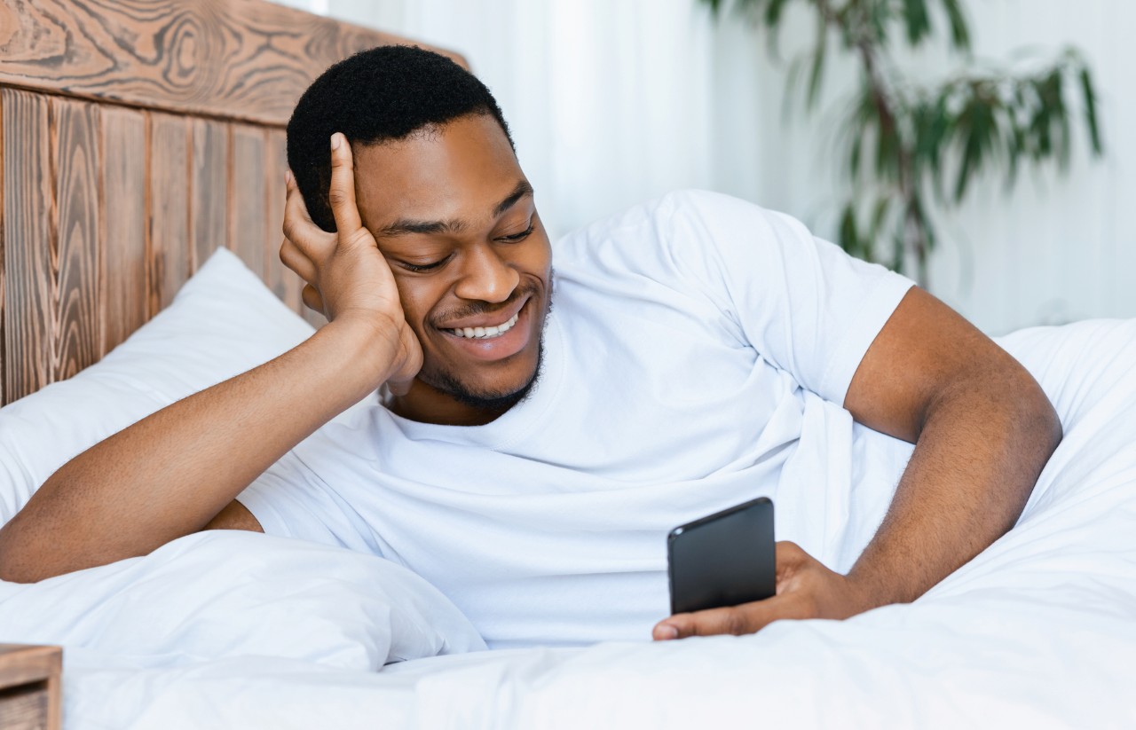 man smiling looking at his smartphone