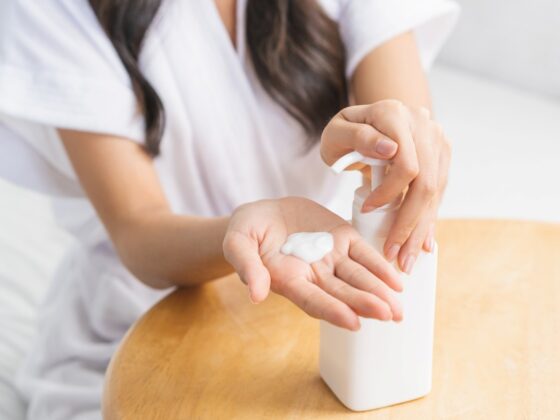 woman squeezing out lotion from a bottle