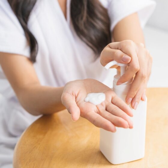 woman squeezing out lotion from a bottle