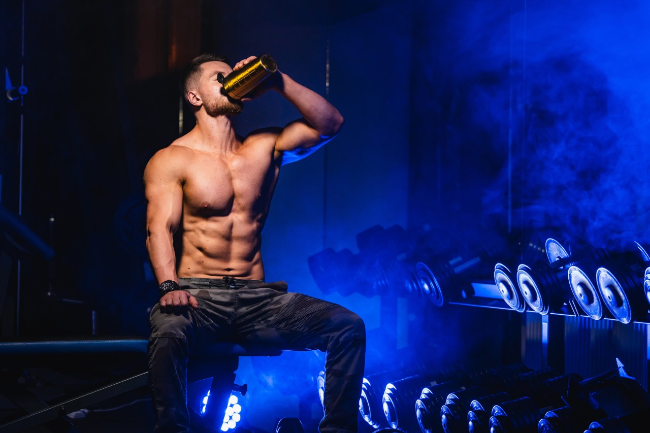 man drinking pre-workout in a gym