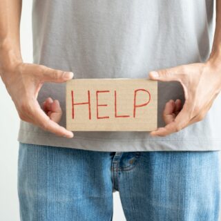man holding a sign with the word help written in front of his pelvis