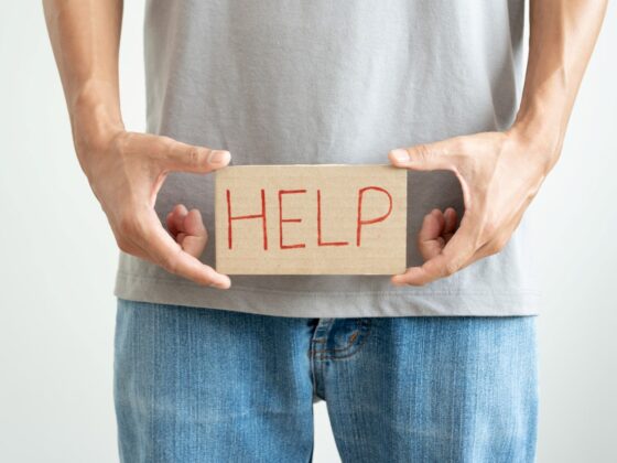 man holding a sign with the word help written in front of his pelvis