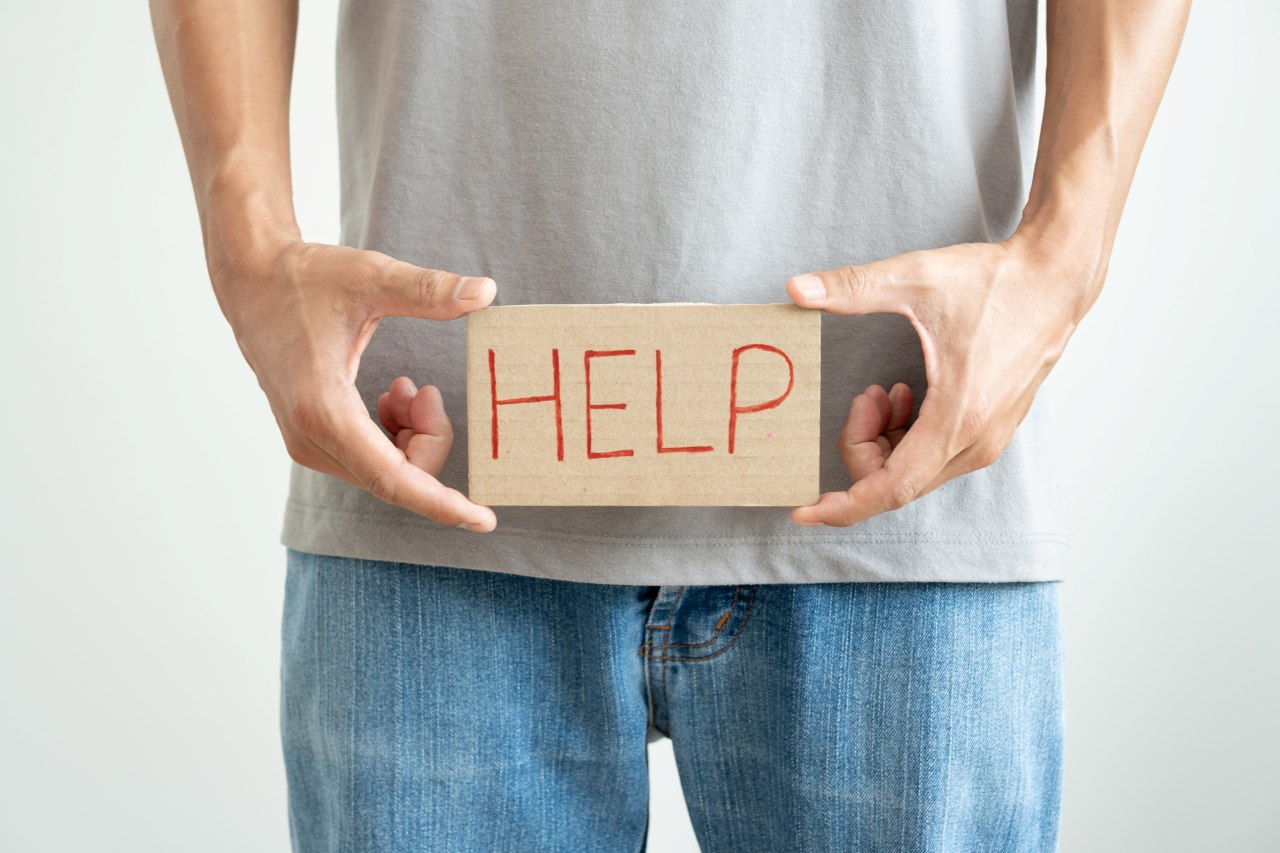 man holding a sign with the word help written in front of his pelvis