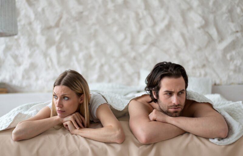 Stressed young couple lying in bed