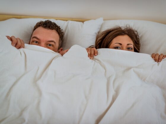 couple in bed hiding under a blanket
