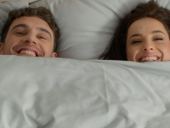 happy smiling couple under a duvet in bed