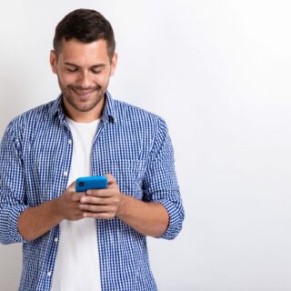 Attractive man standing holding a smartphone in his hands and looking at the screen