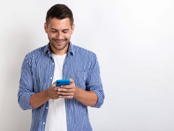 Attractive man standing holding a smartphone in his hands and looking at the screen