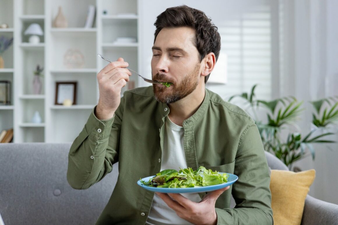 man eating green leafy vegetable using a fork
