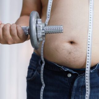 Overweight man exercising by lifting weight with a dumbbell