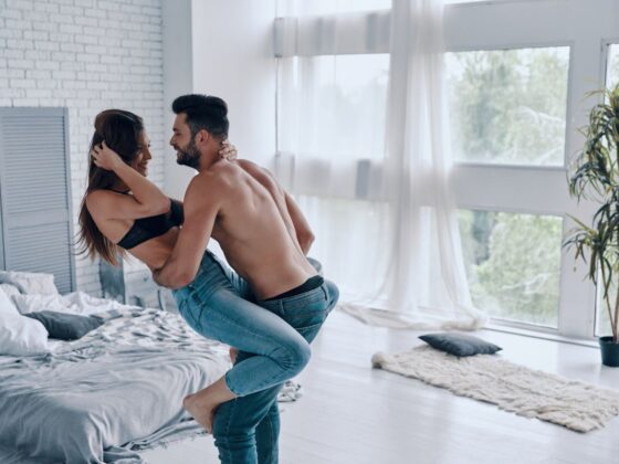 shirtless man carrying semi-dressed attractive woman while standing in the bedroom